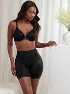 a woman standing in a bedroom wearing a black tummy control short body shaper all-groups