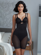 a woman standing in a bedroom wearing a black open bust torsette body shaper sheer shapewear all-groups