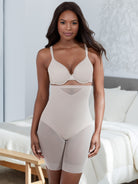 a woman standing in a bedroom wearing a nude high waisted sheer shapewear short body shaper all-groups