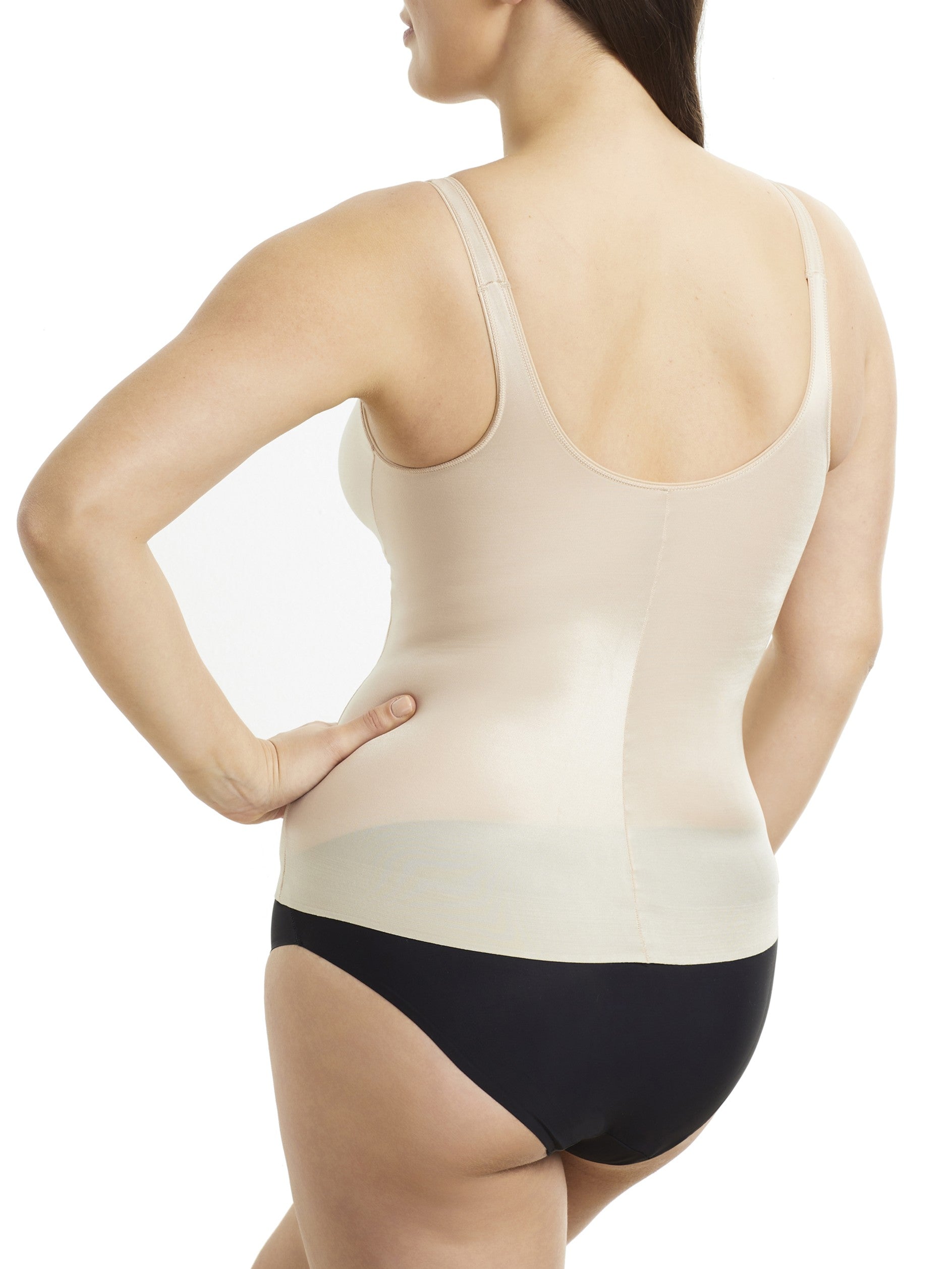 Woman wearing a beige shapewear tank top and black underwear on a white background