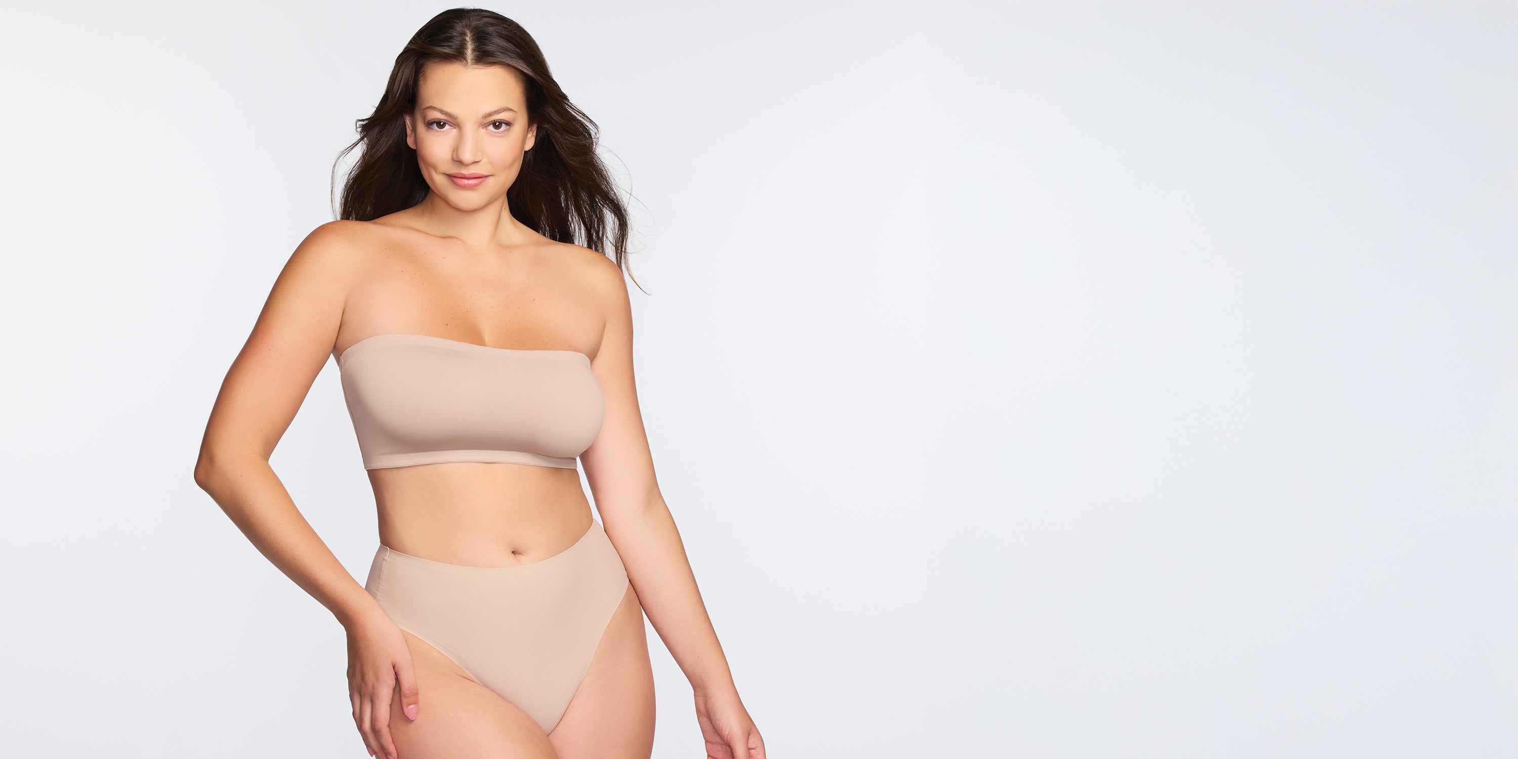 a woman wearing a nude bandeau bralette and a nude high-cut brief panty