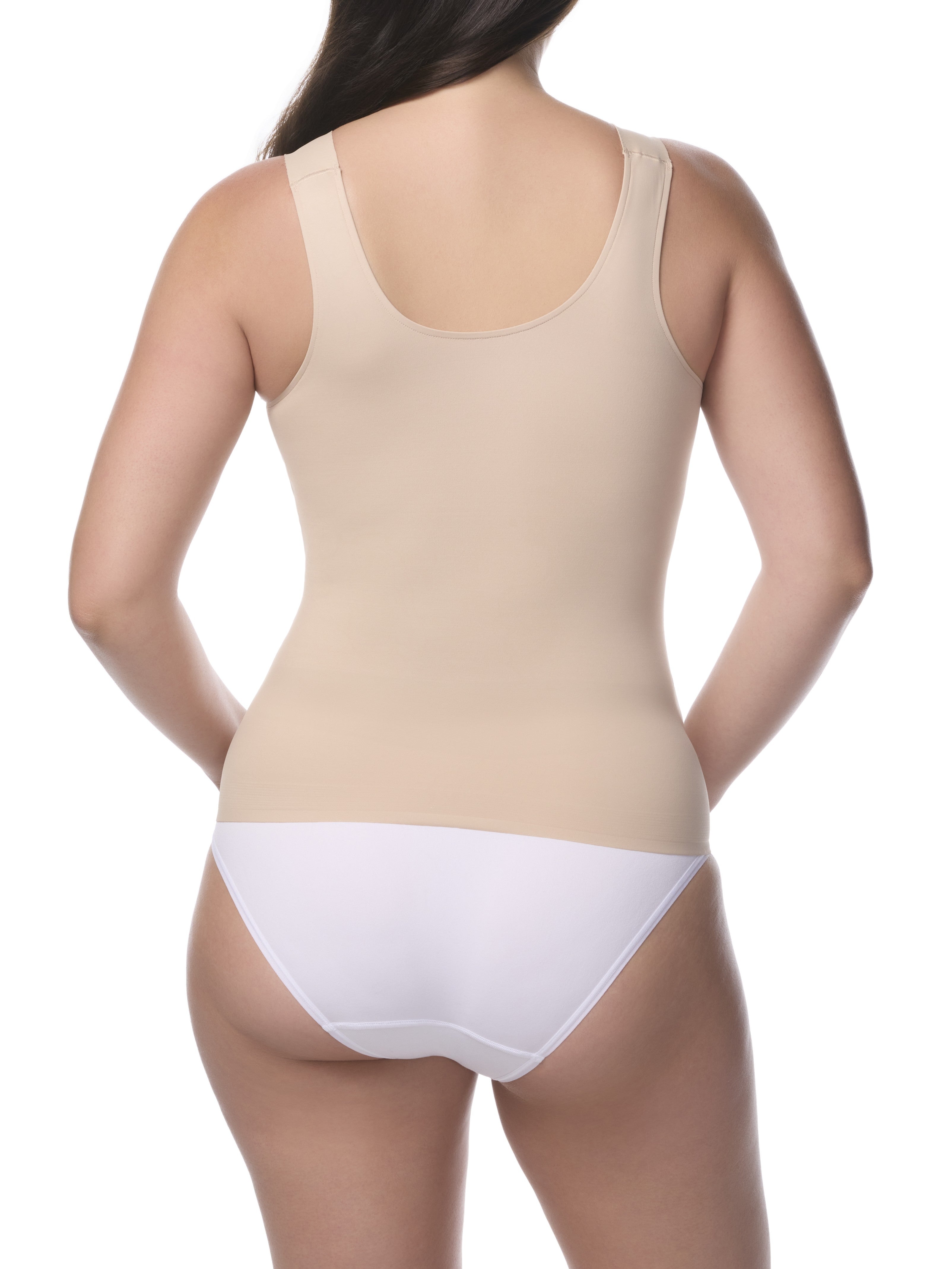 Woman wearing a beige shaping camisole and white underwear on a white background