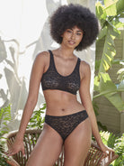 a woman standing outside over a chair wearing a black lace bralette