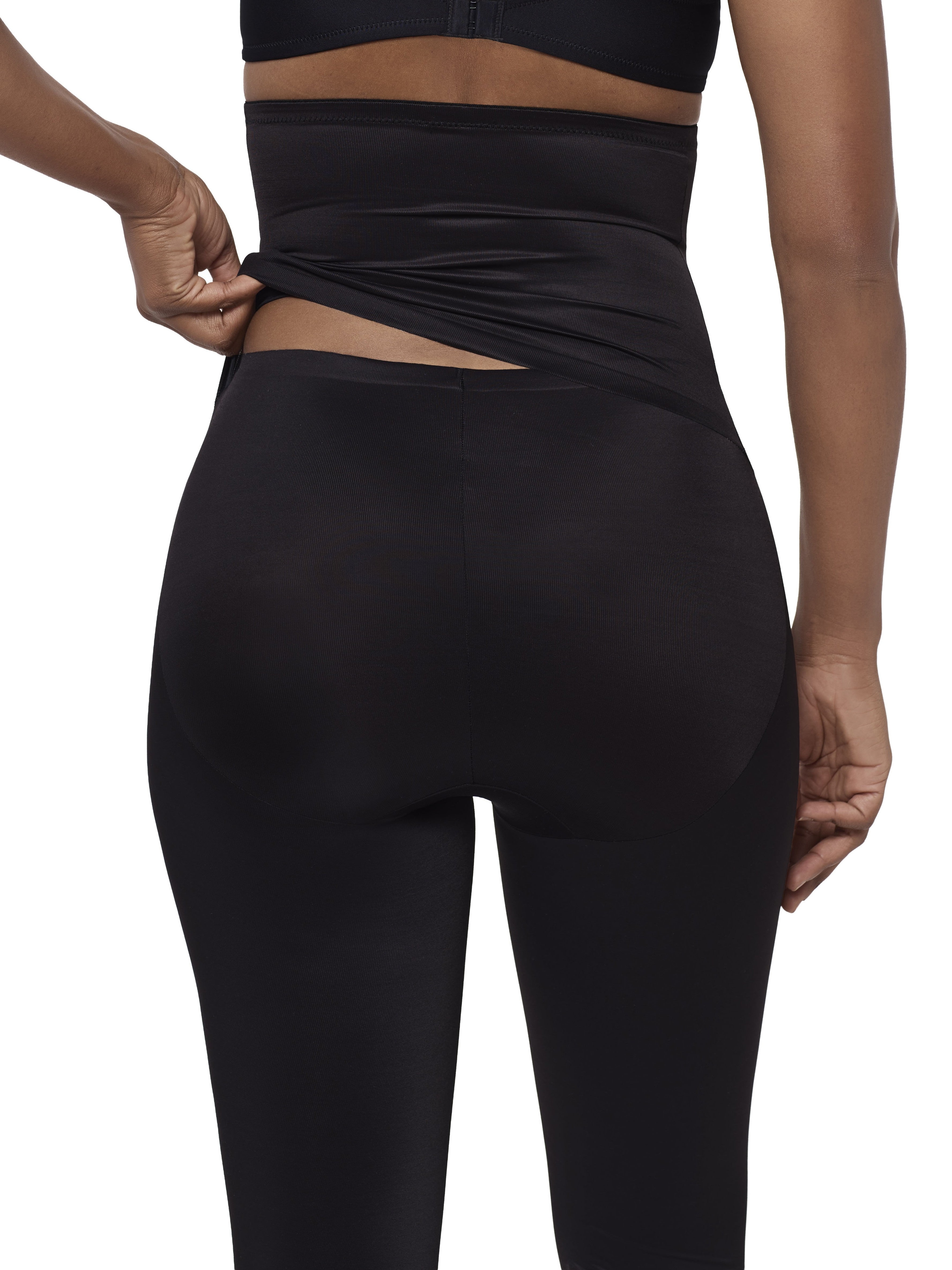 Rear view of a model wearing black high-waisted leggings lifting up the waistband