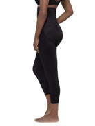 A side-profile view of a model wearing high-waisted black shapewear leggings against a plain white background.