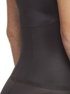 a close-up detail a woman wearing a black open bust tummy control body shaper