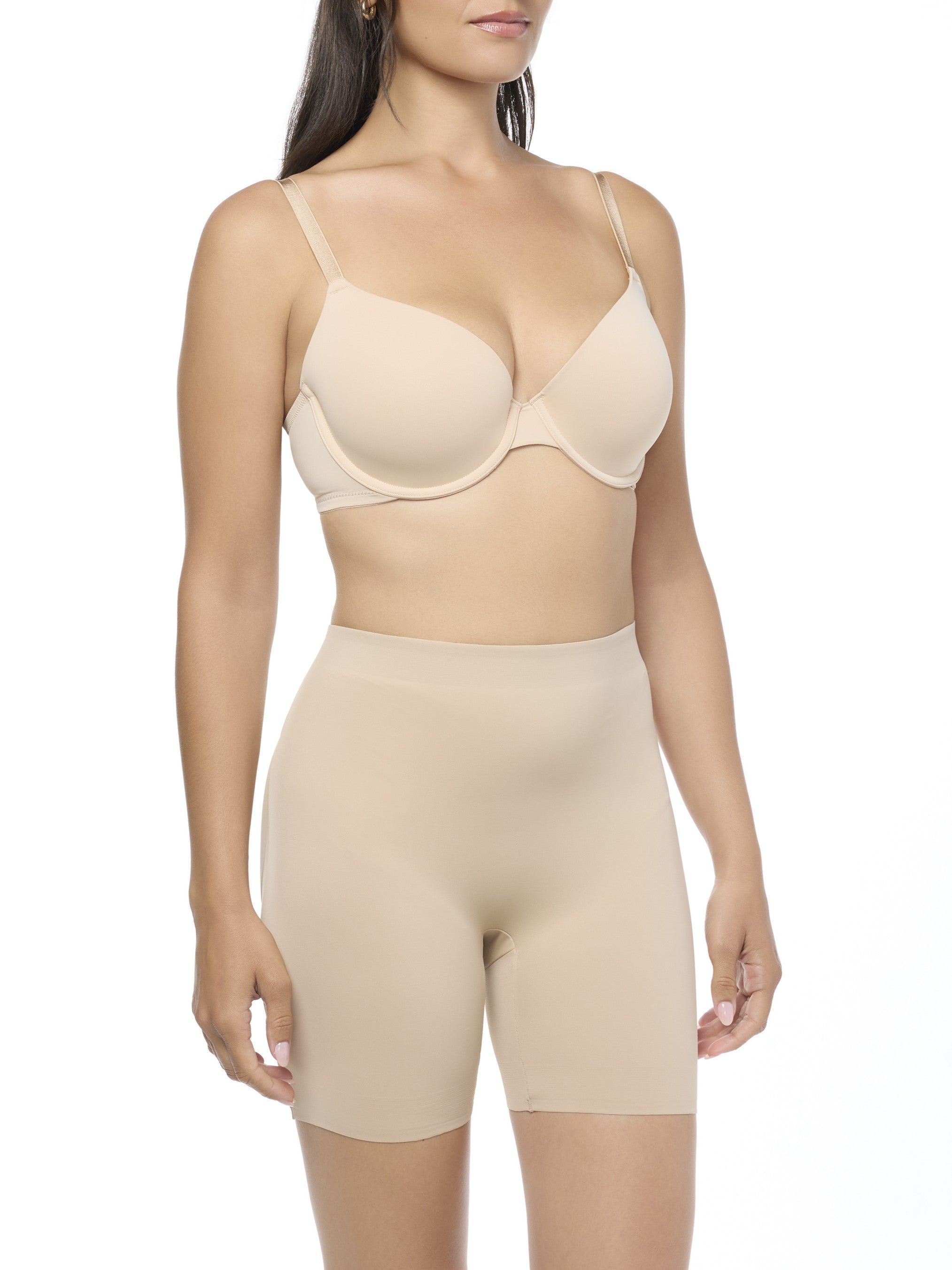 Woman wearing a beige bra and shaping short on a white background