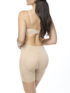 Woman wearing a beige bra and shaping short on a white background