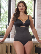 a woman standing in a kitchen leaning on a counter wearing a black waist cincher girdle tummy control shaper shapewear waist trainer all-groups
