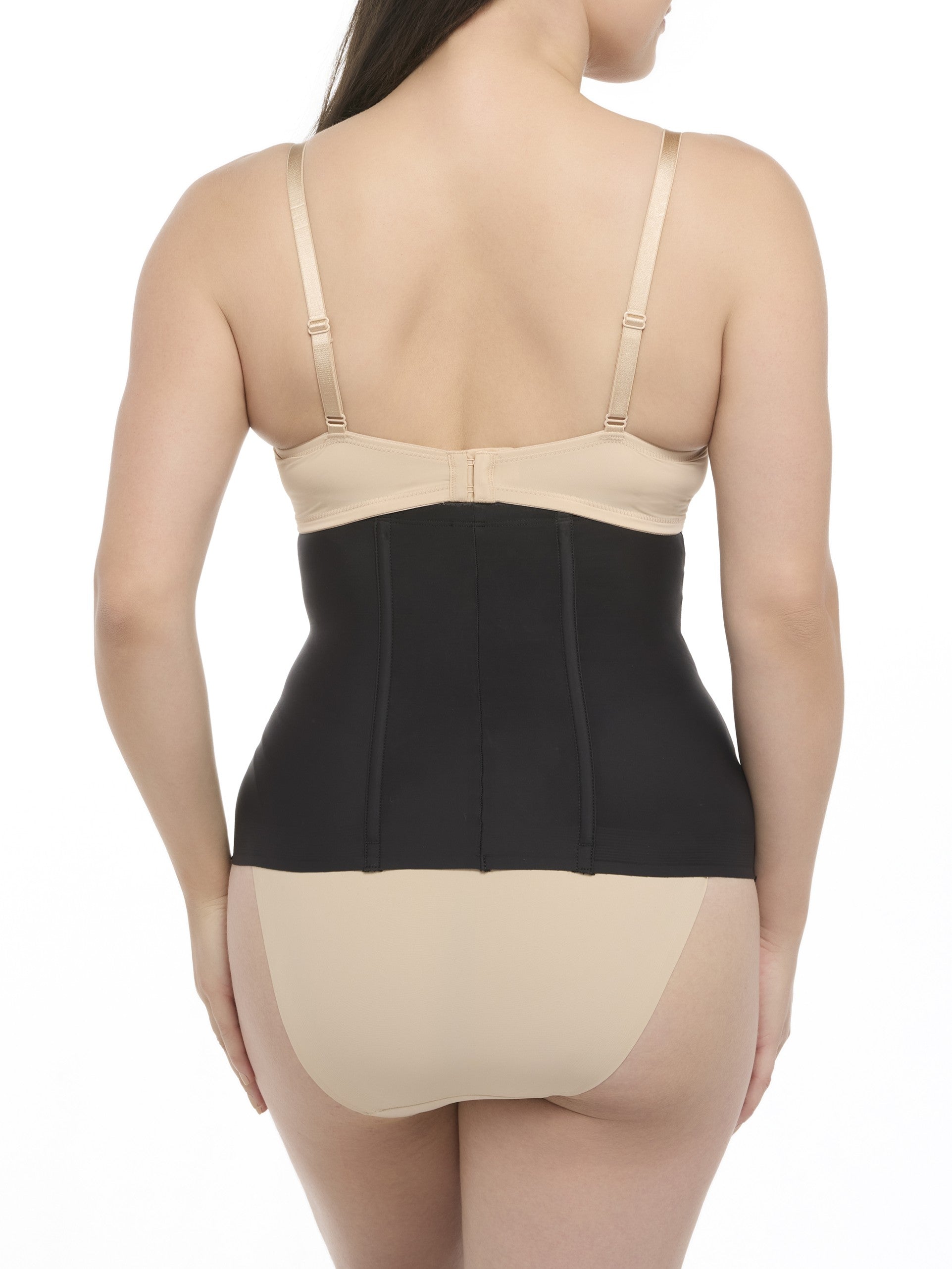 Woman wearing a beige bra and black waist cincher on a white background