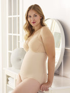 a woman wearing a beige nude high waisted tummy control brief body shaper while standing in a bathroom