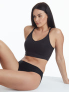 a woman sitting down wearing a black shaping wireless bra bralette