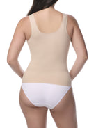 Woman wearing a beige shaping camisole and white underwear on a white background
