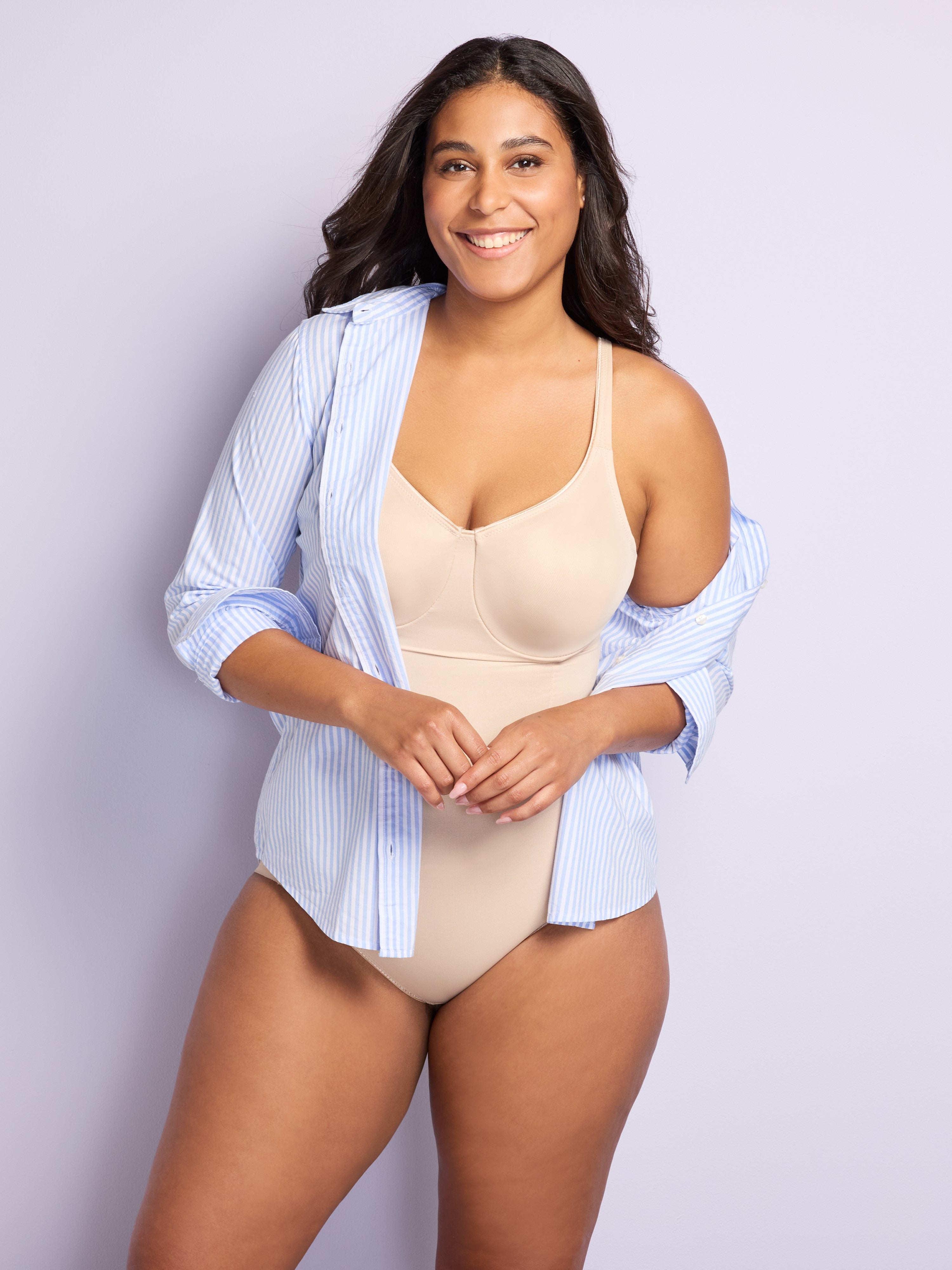 a woman wearing a nude tummy control body shaper shapewear and a blue striped button-front shirt all-groups